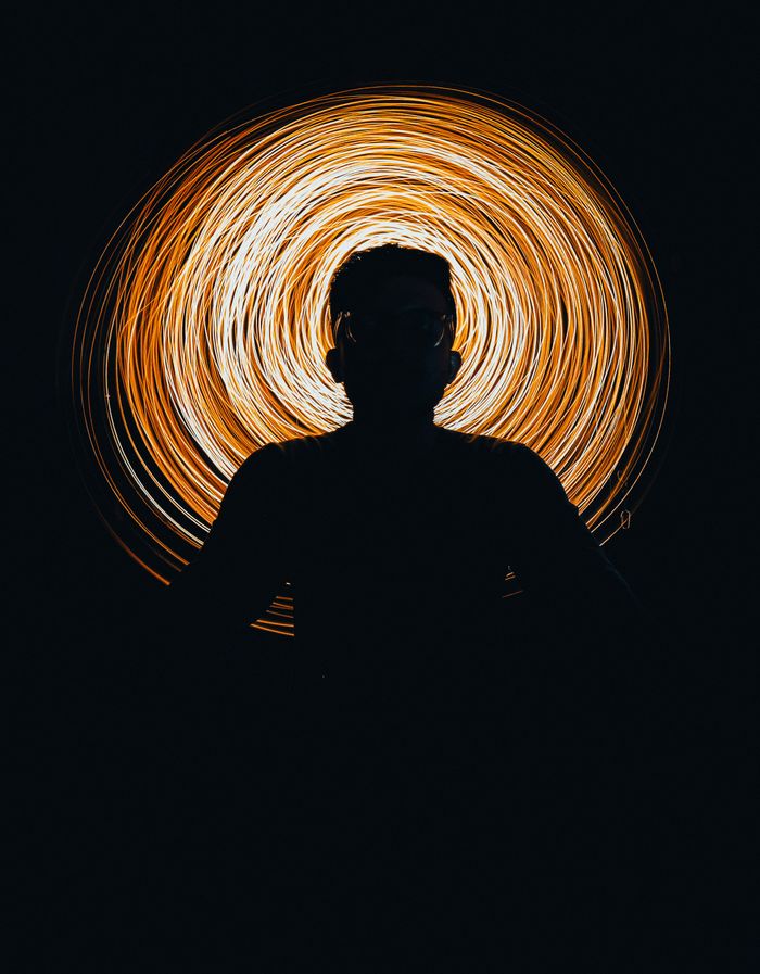 Silhouette against swirling golden light, creating dynamic artistic visual.